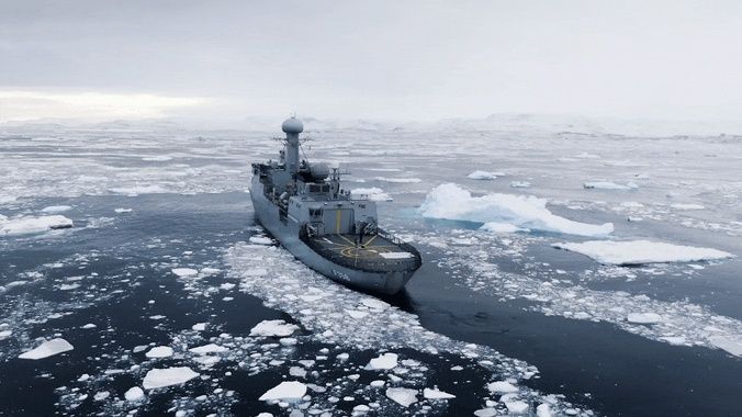 Grått marinefartøy seiler gjennom isflak i et arktisk havområde